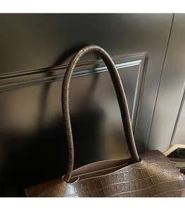 Detailed close-up of dark brown crocodile embossed leather and sturdy shoulder strap