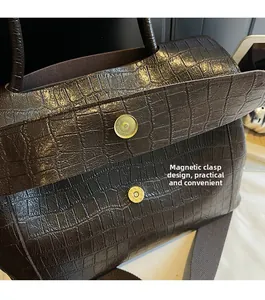 Detailed close-up of dark brown crocodile embossed leather bag with magnetic buckle closure