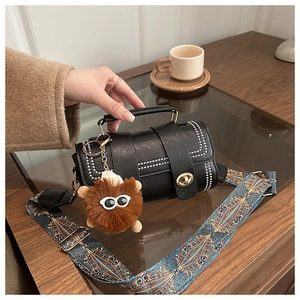 Détail du sac en cuir noir avec bandoulière brodée bleue et charm monstre en peluche
