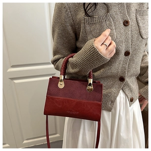 Detail of red patchwork handbag featuring woven handle and gold-tone hardware accents