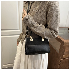 Detail of black patchwork handbag featuring matte texture and gold hardware accents