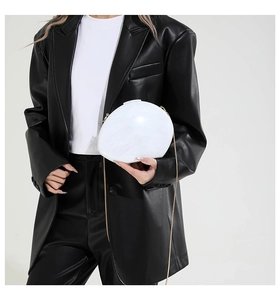 Detail der marmorierten Muschel-Clutch mit goldener Kette auf schwarzem Lederblazer