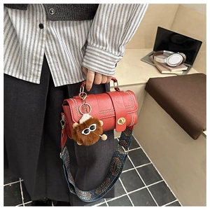 Detail of red vintage leather crossbody bag with ethnic strap and plush lion charm
