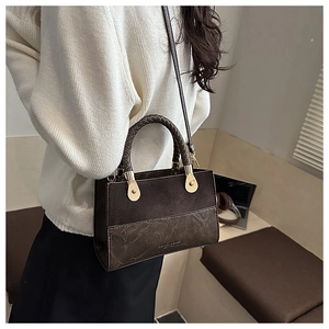 Detail of vintage brown patchwork bag featuring woven handle and gold rivet accents