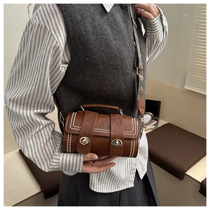 Close-up of brown retro cylindrical bag with floral strap and metal double twist locks