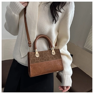 Detailed shot of a brown patchwork handbag featuring leopard print suede and woven handle