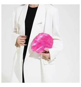 Detail of pink marble acrylic clutch bag with gold chain strap held by a model