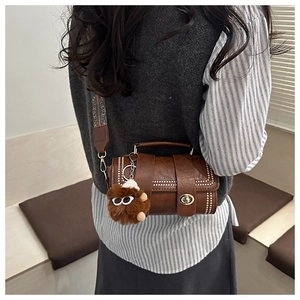 Detail of retro brown cylinder crossbody bag with rivets and ethnic pattern wide strap