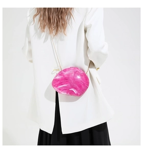 Detail of fuchsia marble acrylic box bag with a delicate gold chain on a model