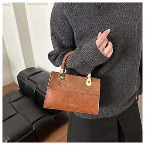 Detail of a brown patchwork handbag with frosted leather texture and woven handle