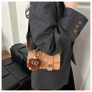 Close-up of retro brown shoulder bag with vintage metal lock and plush monster charm