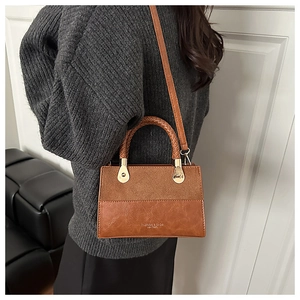 Detail view of brown patchwork leather crossbody bag featuring textured handle and gold hardware