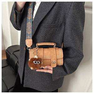 Retro brown leather cylinder bag with wavy studs and a geometric fabric strap on a model
