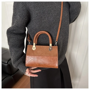 Detail of a brown patchwork leather handbag with woven handle and embossed logo