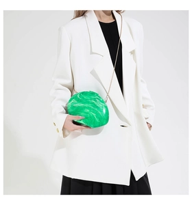 Green marble pattern acrylic clutch bag with gold chain strap shown on model's shoulder