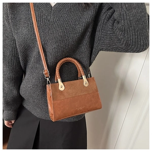 Detail of retro brown patchwork handbag with braided handle and gold-tone hardware links