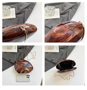 Details der bernsteinfarbenen Acryl-Clutch mit Goldkette und Innenfutter-Stauraum