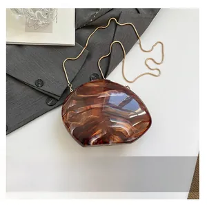Detail der Acryl-Clutch mit Marmormuster und Goldkette neben einem Smartphone als Maßstab