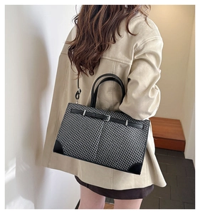 Détail du sac cabas en pied-de-poule avec bordure en cuir noir porté par un mannequin