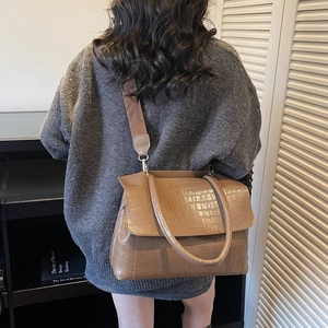 Brown crocodile embossed tote bag with wide strap shown on model in a modern interior