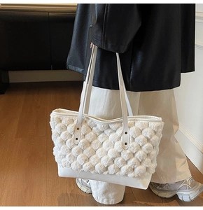 Close-up of beige plush bubble texture tote bag with leather straps and metal rivets