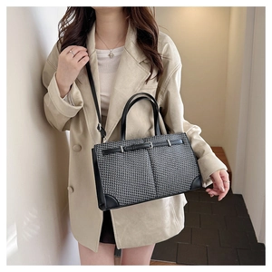 Détail d'un sac cabas à motif pied-de-poule porté avec un blazer pour l'échelle et texture