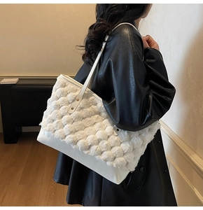 Detail of white faux fur tote bag showing plush woven texture and sleek leather base