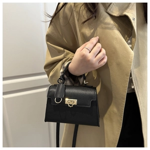 Dettaglio mini borsa in pelle nera a grana di litchi con fibbia dorata su trench beige
