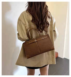 Détail du sac fourre-tout tressé marron montrant la texture et la boucle en cuir