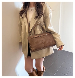 Détail d'un sac cabas tissé marron foncé avec finitions en cuir et bandoulière