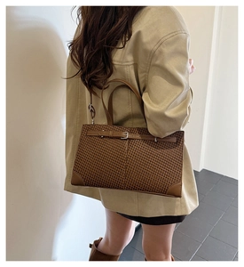 Détail du sac cabas marron tissé avec lanières en cuir foncé et boucle métallique chic