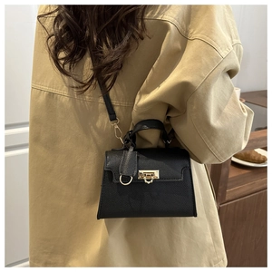 Detailansicht der schwarzen Kelly-Tasche aus Leder mit goldenen Elementen an einem Model
