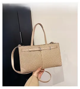 Détail du sac cabas tissé avec bordure en similicuir et boucle décorative sur la sangle