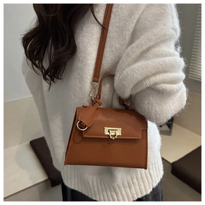 Braune Kelly-Tasche aus Leder mit Litschi-Textur zu einem weißen Strickpullover