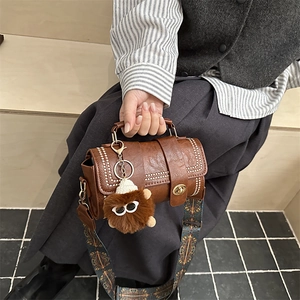 Sac à main cylindrique marron vintage avec bandoulière large et pendentif monstre