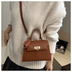 Dettaglio mini borsa in pelle marrone martellata con chiusura dorata e tracolla regolabile