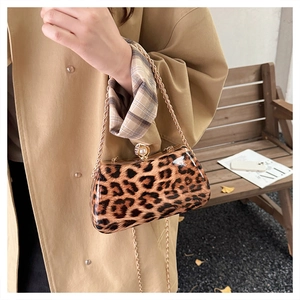 Detail of leopard print handbag with glossy finish, pearl clasp, and gold chain strap