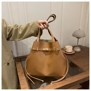 Detail of vintage brown tote bag featuring golden turn-lock closure and side drawstring