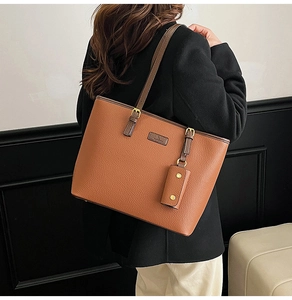 Close-up of brown litchi pattern leather tote bag with logo and mini bag accessory