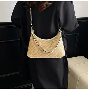 Détail du sac hobo à motif monogramme vintage et chaîne dorée sur manteau noir