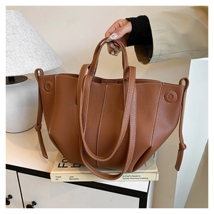 Detailed view of brown litchi grain leather tote bag with white contrast stitching