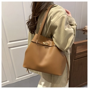 Close-up of caramel brown tote bag featuring elegant gold clasp and side drawstring details