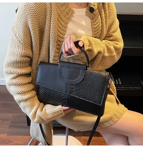Detail of black mixed-texture handbag with snakeskin pattern and leather strap