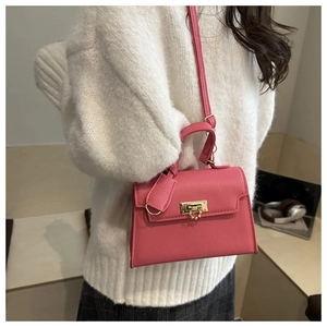 Dettaglio della mini borsa Kelly in pelle fucsia con chiusura a scatto dorata