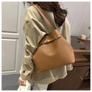 Detail of camel brown tote bag featuring matte texture and golden metal twist-lock buckle