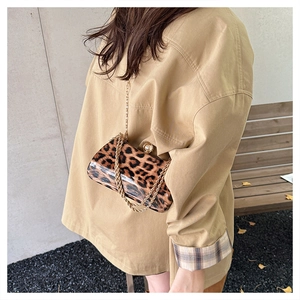 Detail of leopard print handbag with pearl buckle and gold chain strap on model