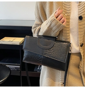 Detail of black snake pattern handbag featuring mixed textures and metal handle