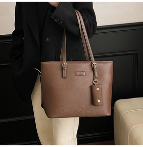 Detail of dark brown pebble leather tote bag with gold buckle and small hanging pouch