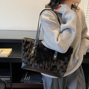 Minimalist large black fuzzy tote bag with leather handles shown in a lifestyle setting