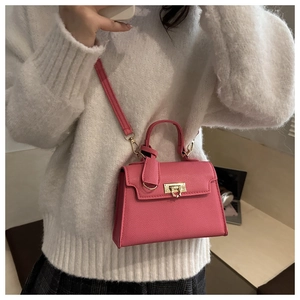 Dettaglio borsa a mano rosa in pelle martellata con chiusura dorata su maglione bianco